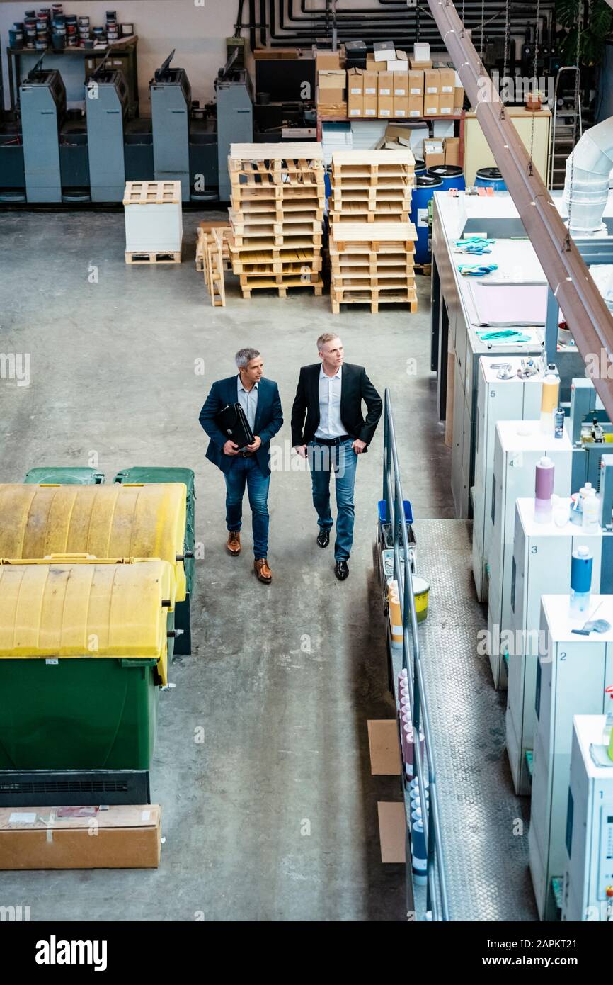 Two businessmen walking and talking in a factory Stock Photo - Alamy