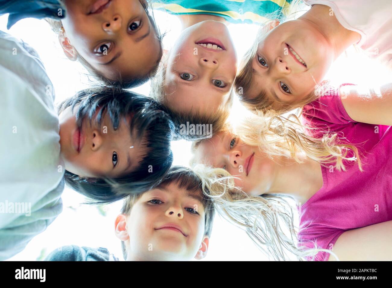Group of children, sticking heads together, upward view Stock Photo