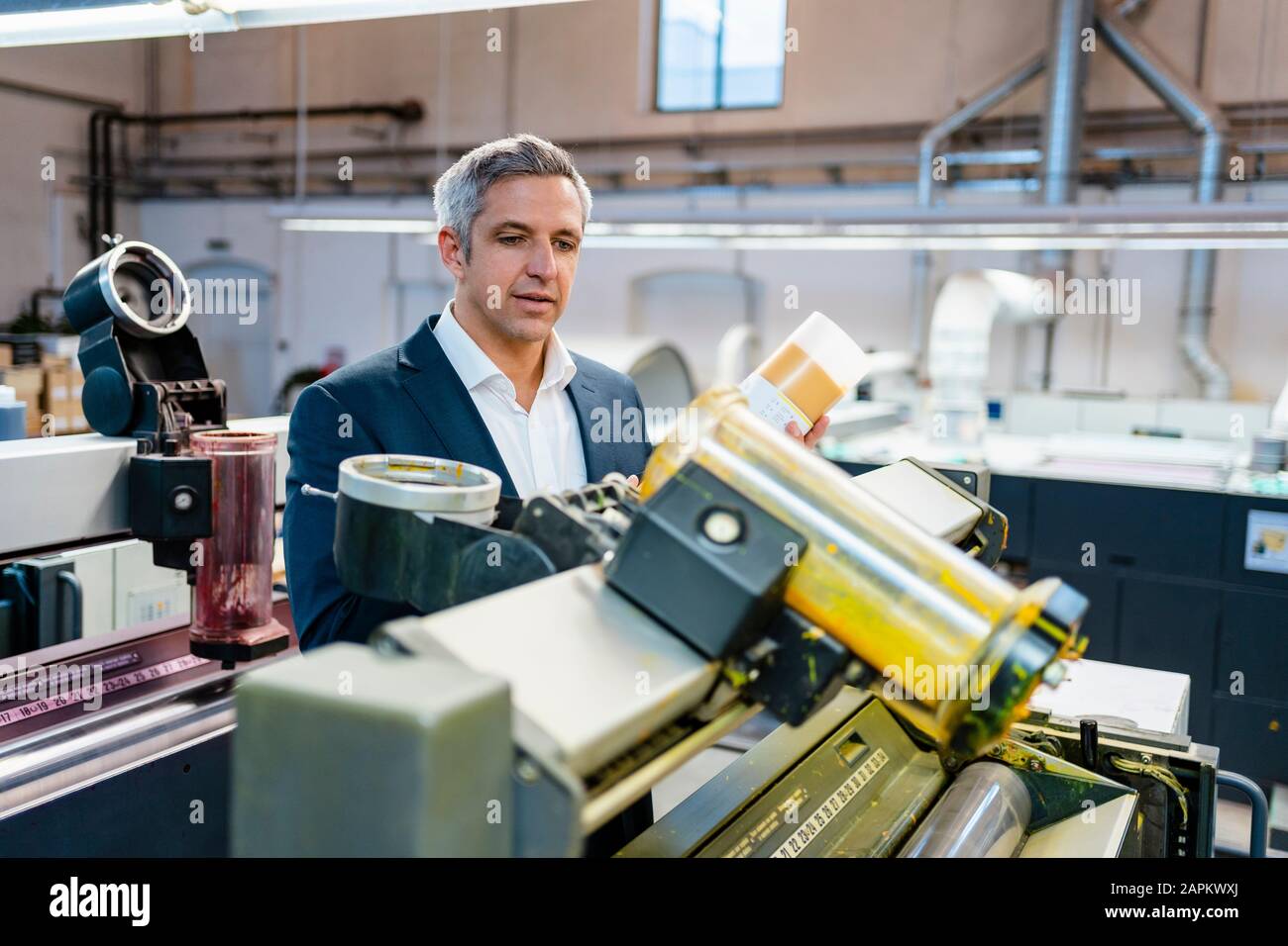 Businessman in a factory looking at a machine Stock Photo