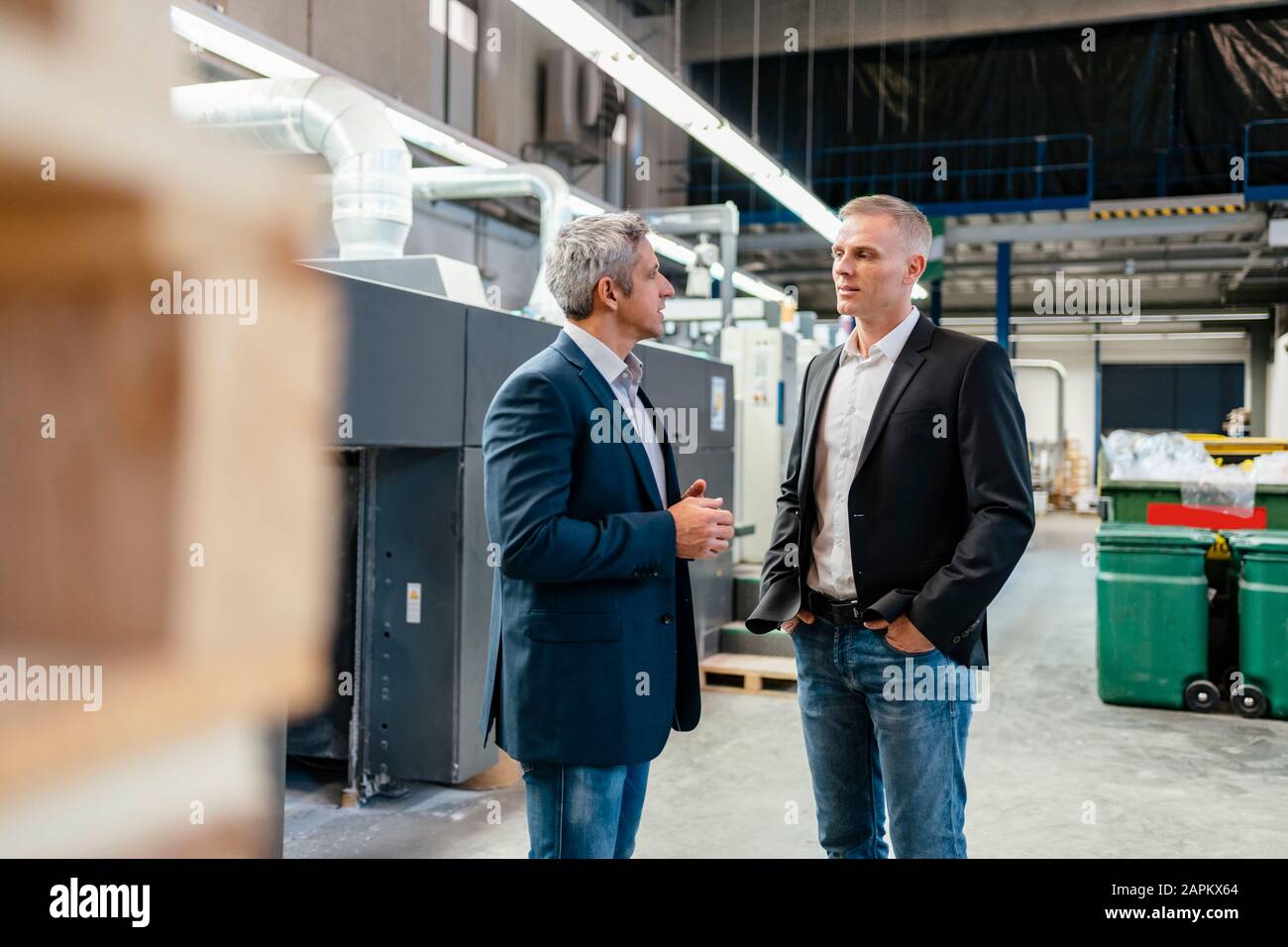 Two businessmen talking in a factory Stock Photo - Alamy