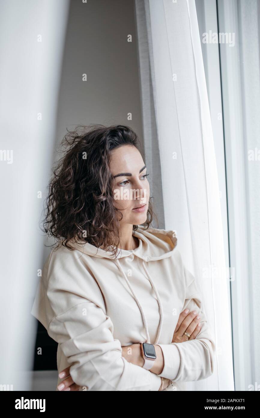 Portrait of pensive woman looking out of window Stock Photo