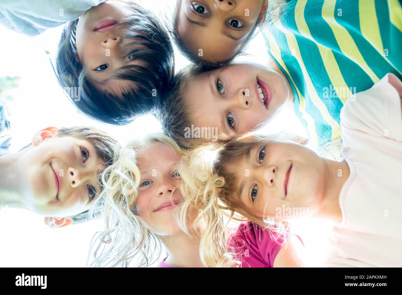 Group of children, sticking heads together, upward view Stock Photo