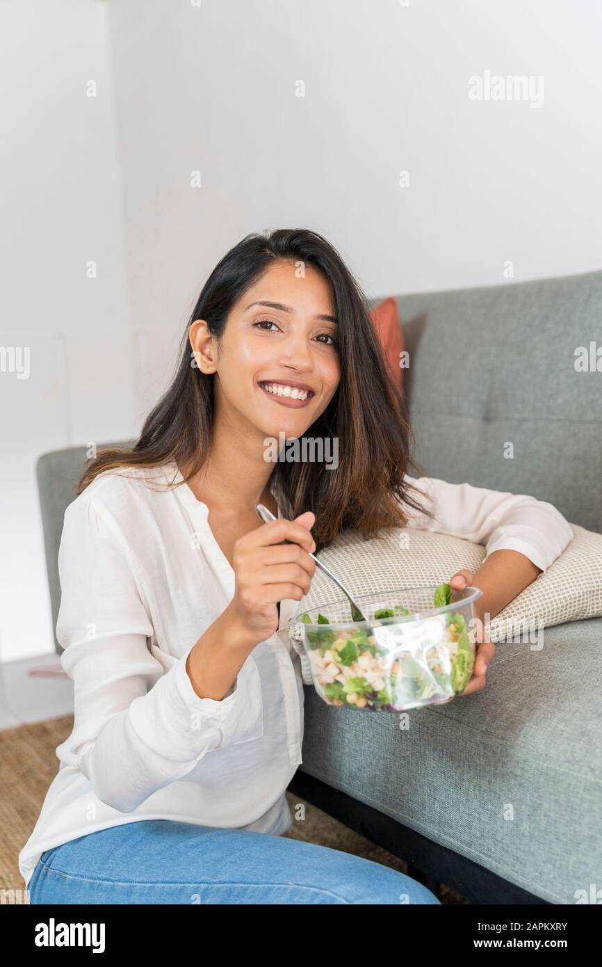 Portrait of relaxed young businesswoman with bowl of mixed salad Stock Photo