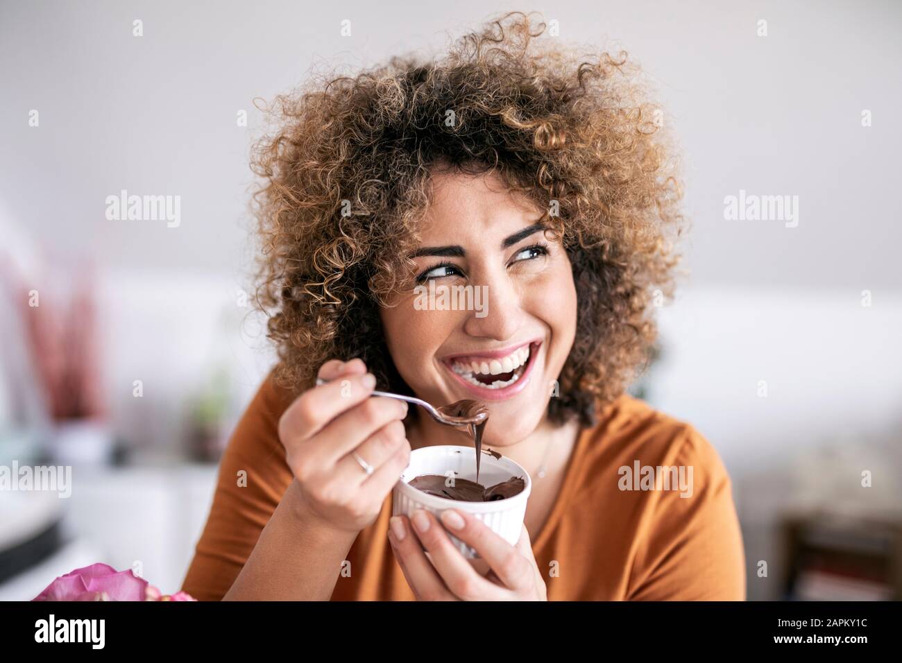 Portrait of happy woman eating chocolate spread at home Stock Photo