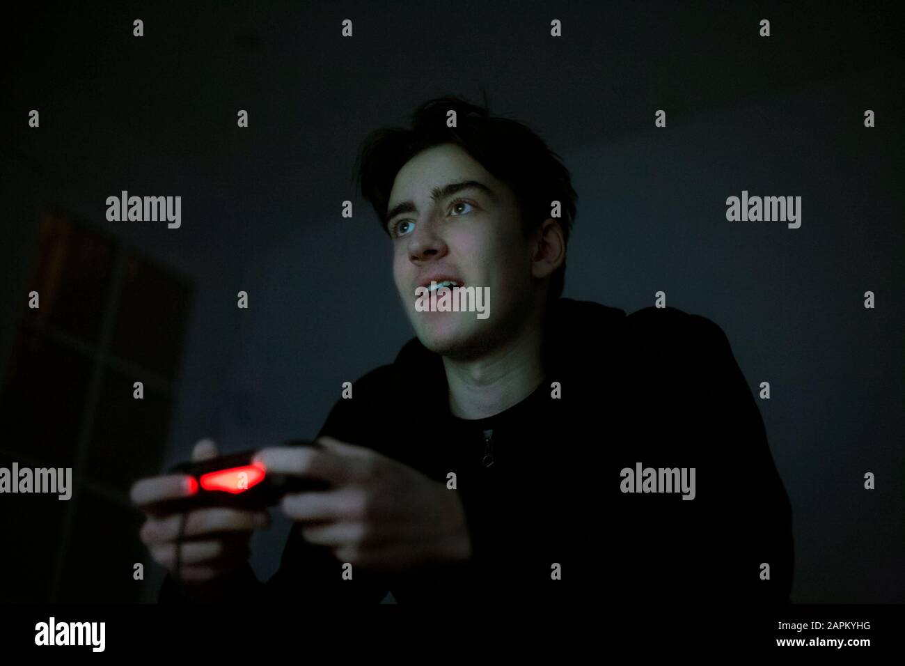 Teenage boy playing video game with console in the dark Stock Photo