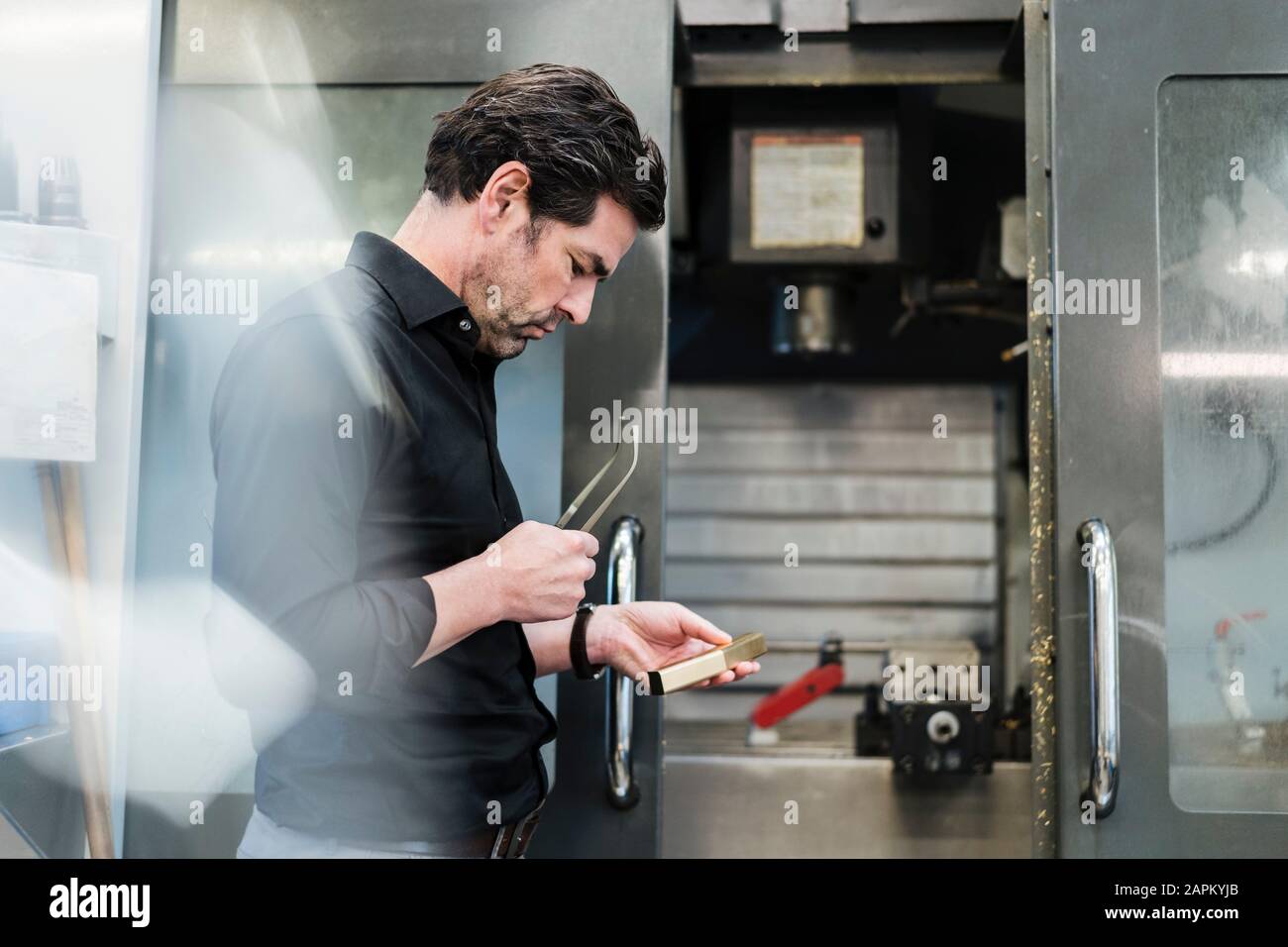 Businessman examining workpiece in a factory Stock Photo
