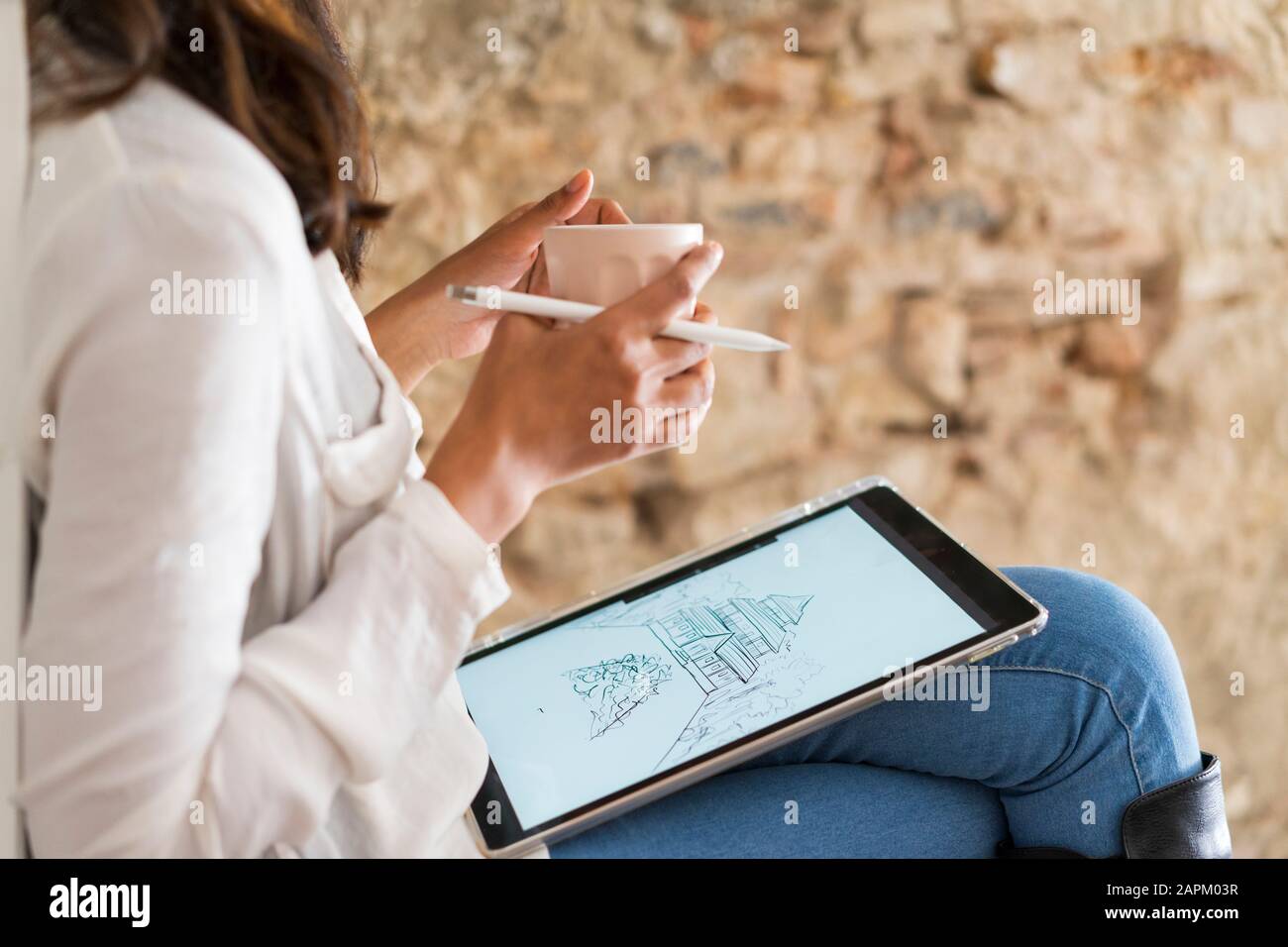 Crop view of young architect with  coffee mug working on digital tablet Stock Photo