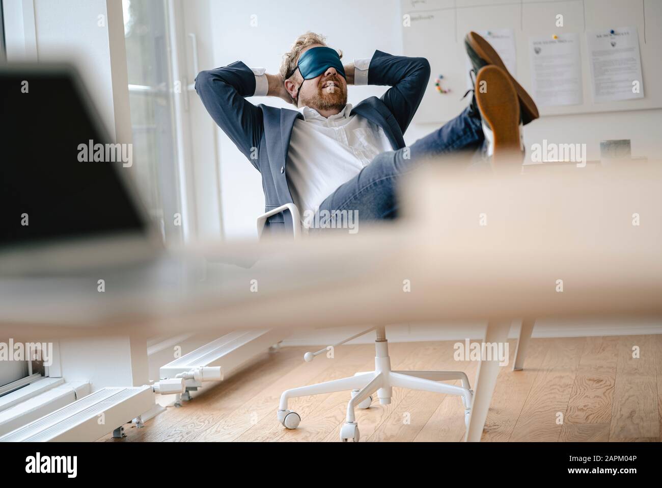 Businessman having a power nap at desk in office Stock Photo