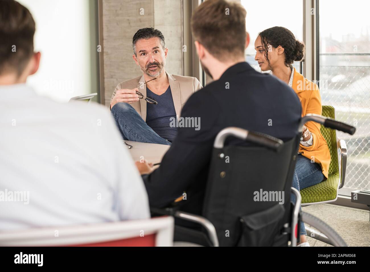 Business people having a meeting in office with one sitting in wheelchair Stock Photo