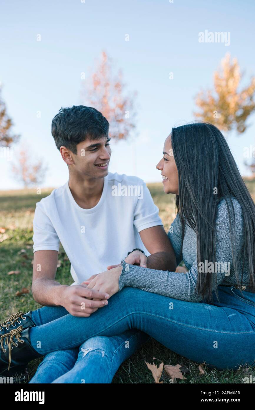 Teenage couple in love sitting on a meadow in autumn Stock Photo