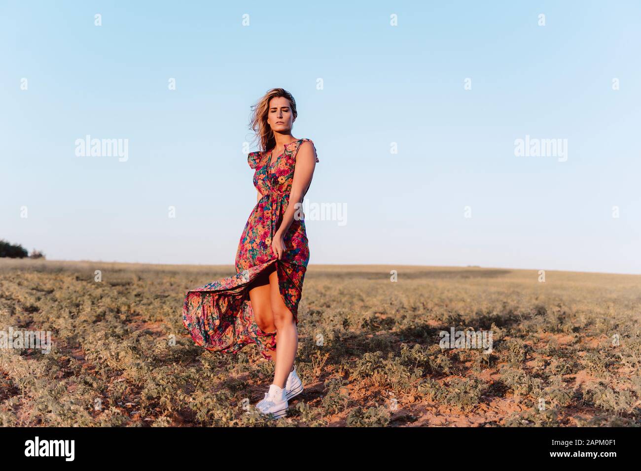 Blond woman wearing summer dress with closed eyes at countryside Stock Photo