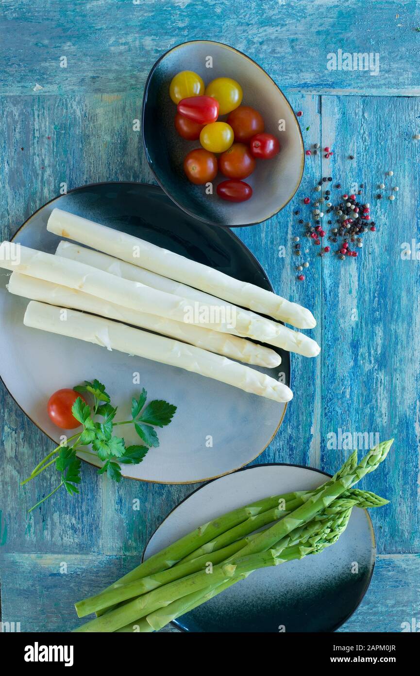 White and green asparagus on rustic wooden background, yellow tomatoes, red tomatoes, colored pepper, parsley Stock Photo