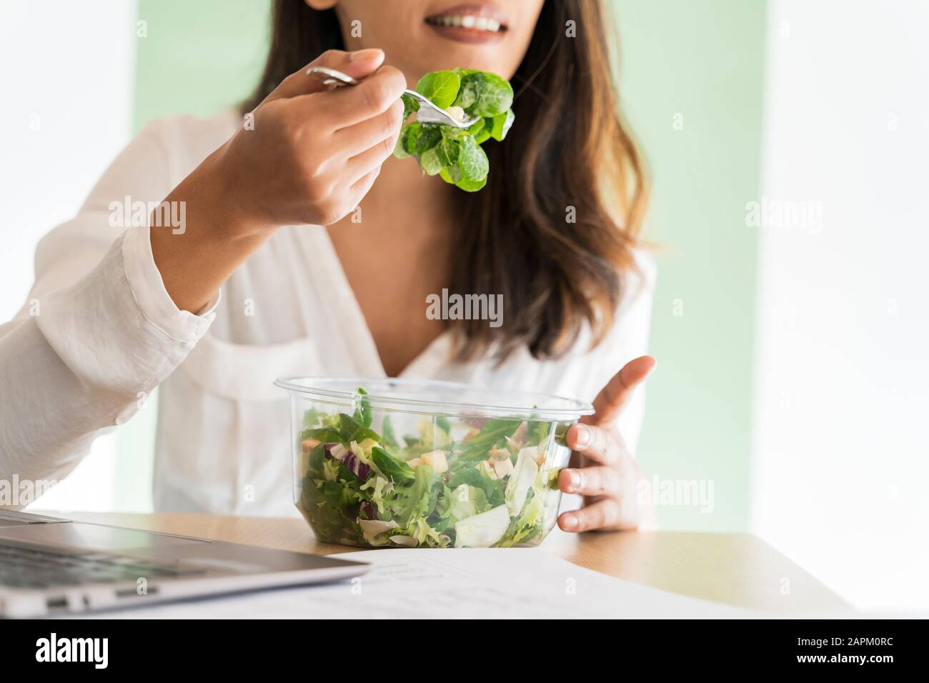 Crop view of young architect eating mixed salad at desk Stock Photo