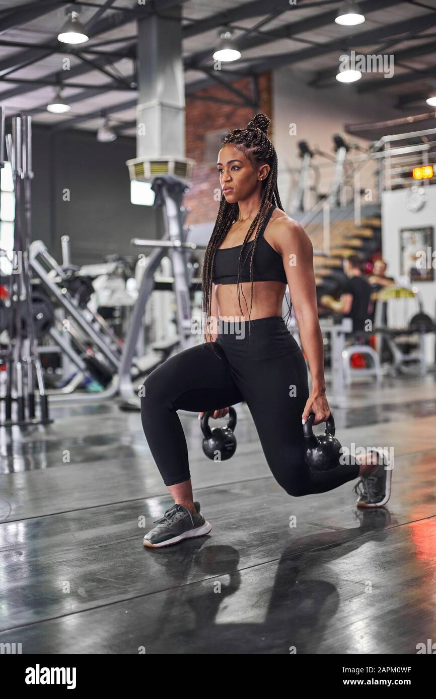 Female athlete doing lunges with kettlebells Stock Photo