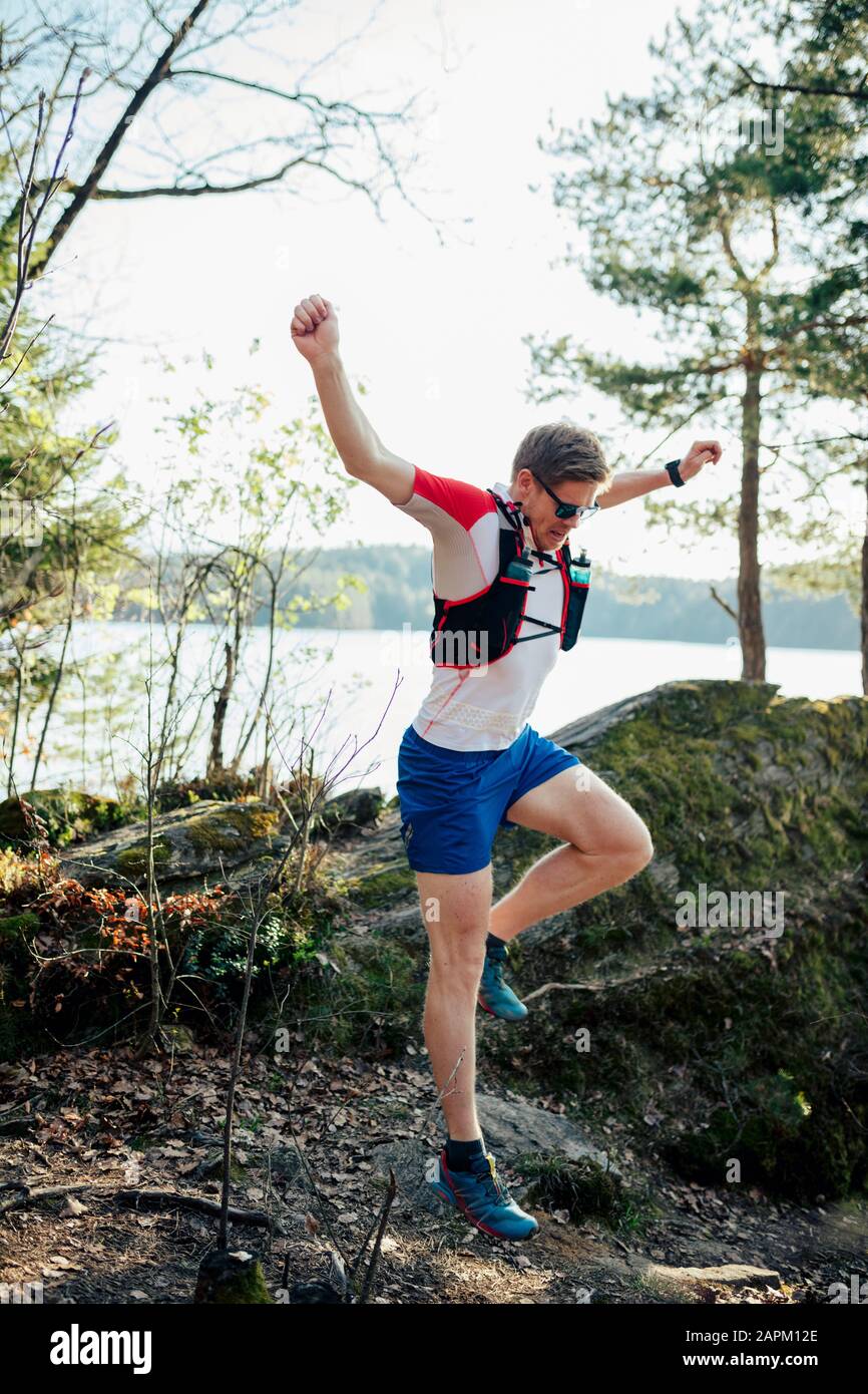 Man running at the lakeside jumping over an obstacle, Forstsee, Carinthia, Austria Stock Photo
