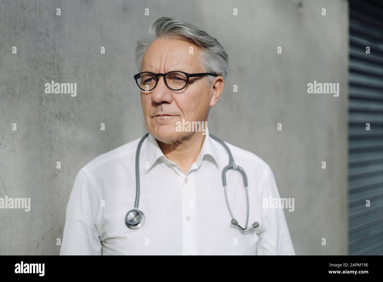 Pensive senior doctor at a concrete wall Stock Photo - Alamy