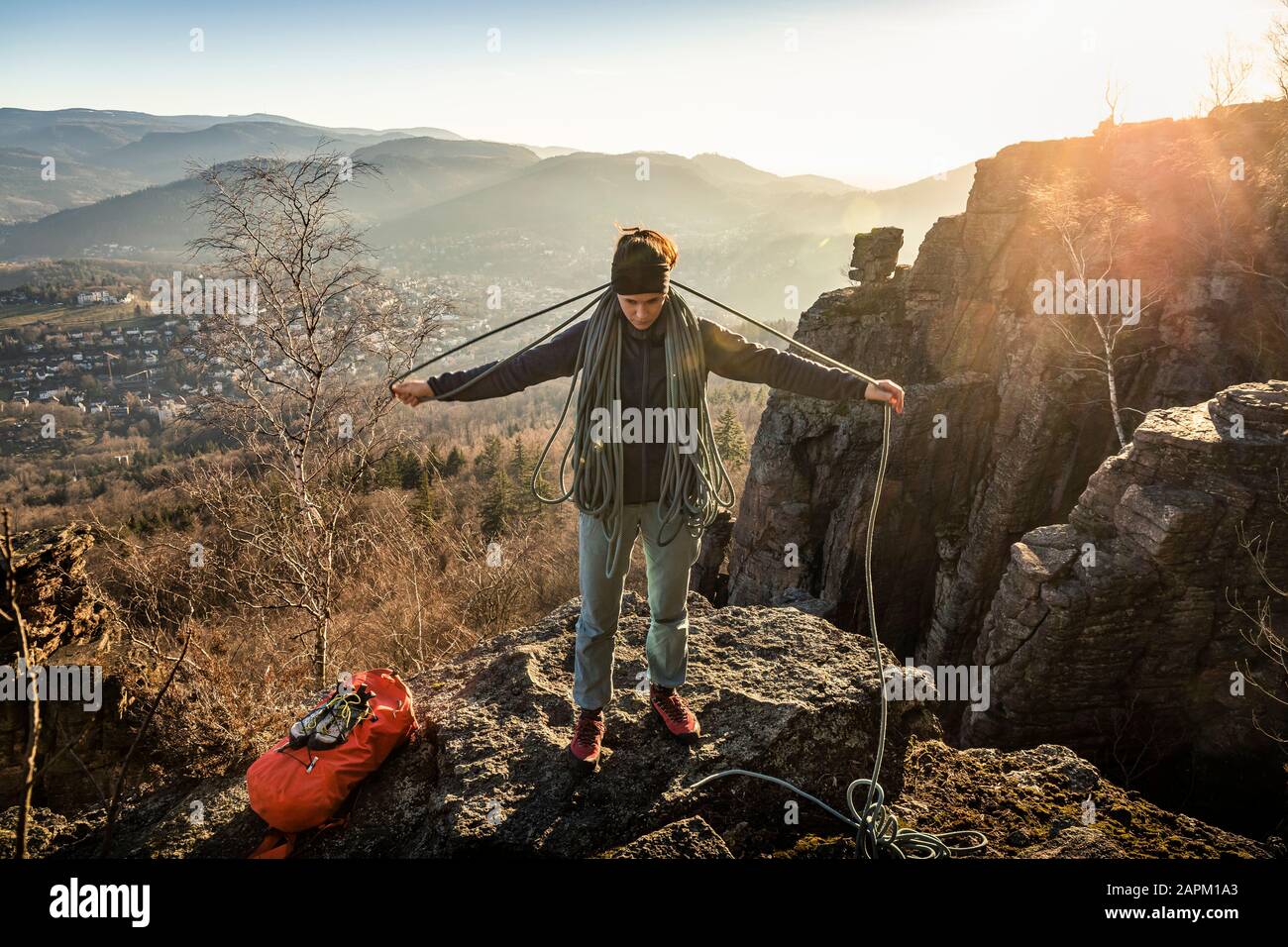 Female climber with rope standing on Battert rock at sunset, Baden