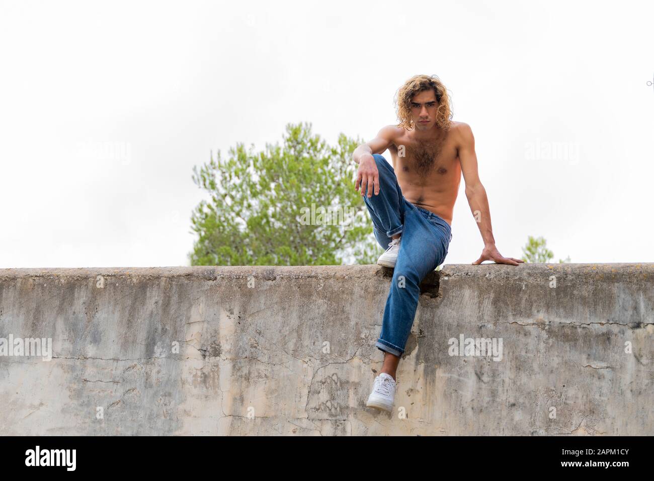 Young blond man sitting on a wall Stock Photo