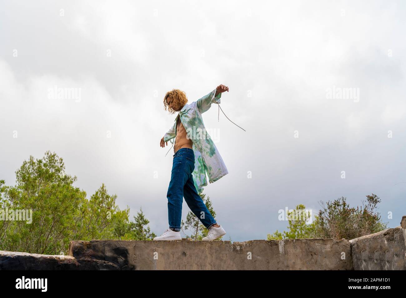 Young blond man balancing on a wall Stock Photo