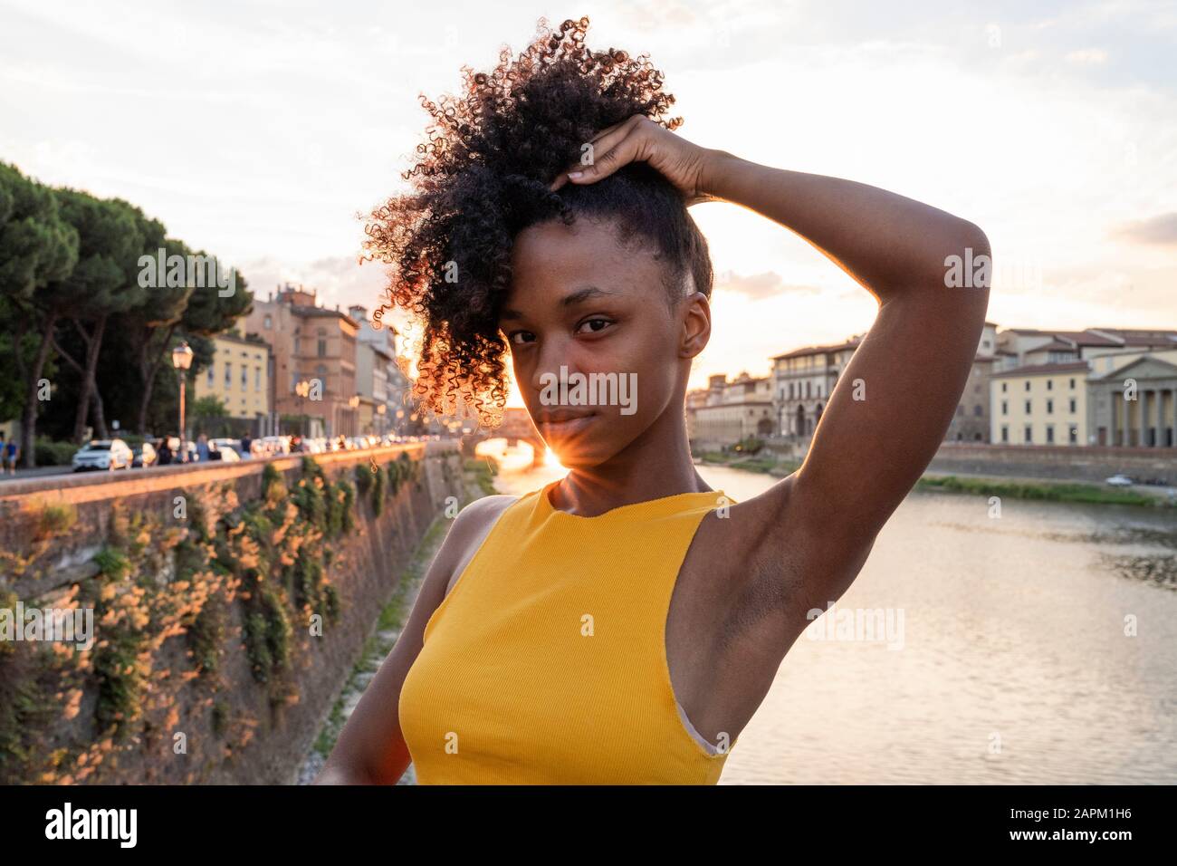 Portrait of a confident young woman at river Arno at sunset, Florence, Italy Stock Photo