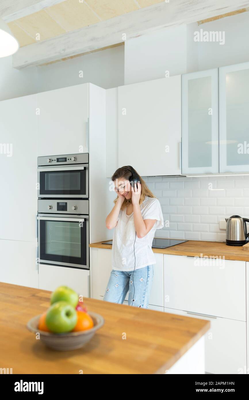 Female teeanger with headphones in the kitchen Stock Photo Alamy
