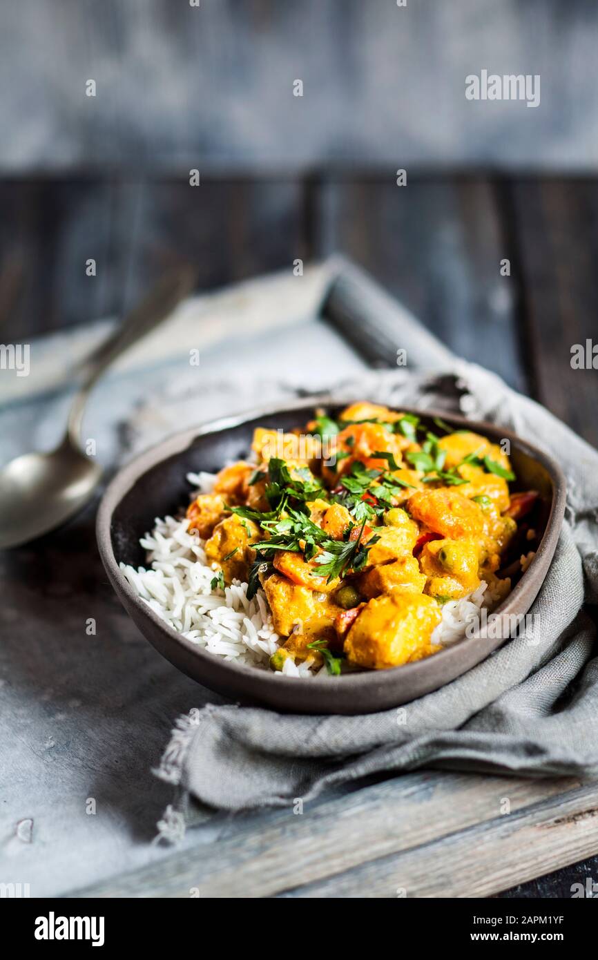 Bowl of vegan curry with potatoes, carrots, peas, parsley and pumpkin
