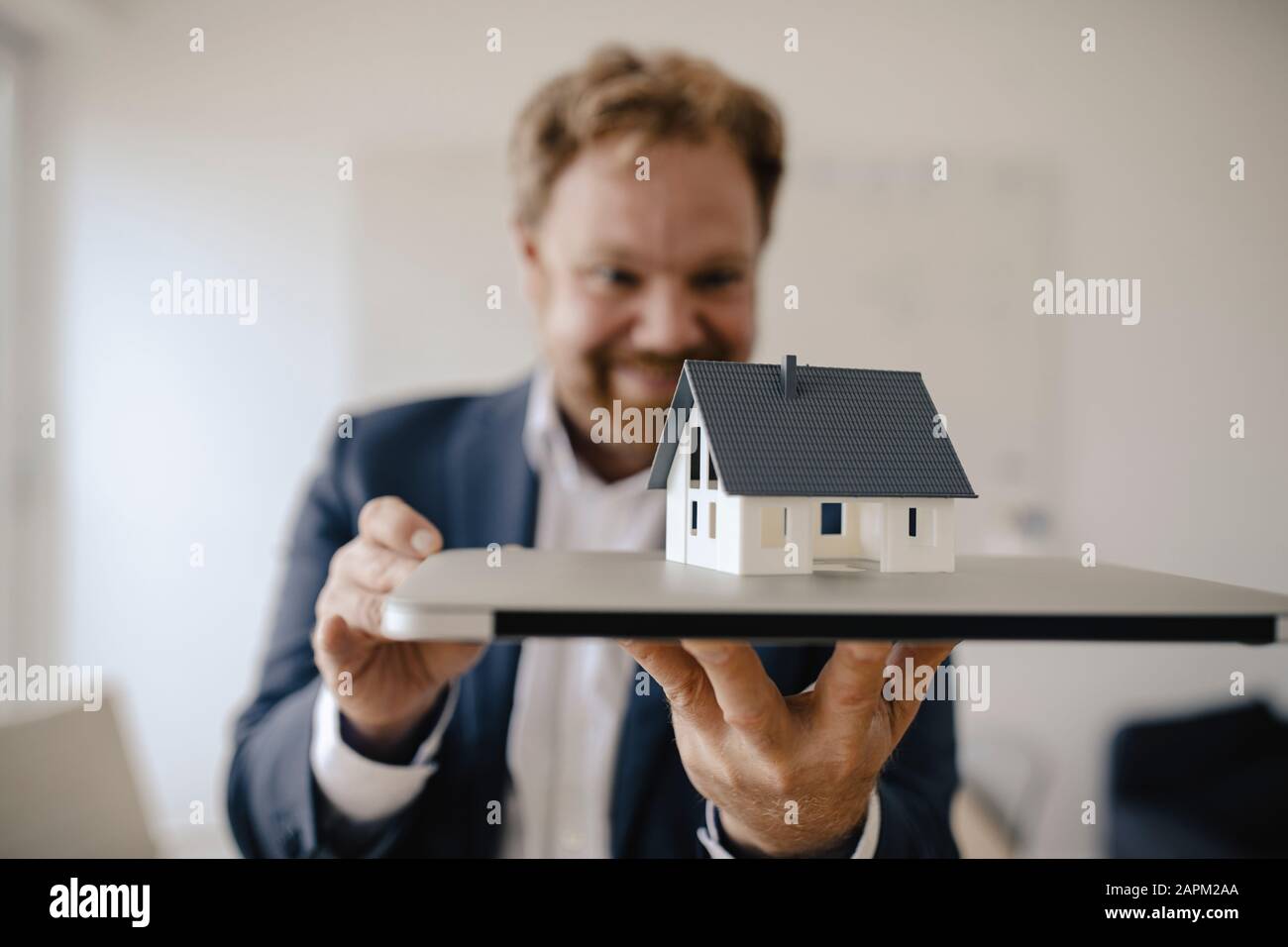 Businessman holding model house in office Stock Photo