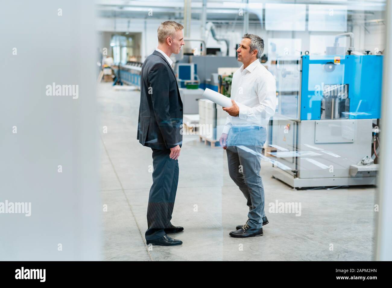 Two businessmen talking in a factory Stock Photo - Alamy