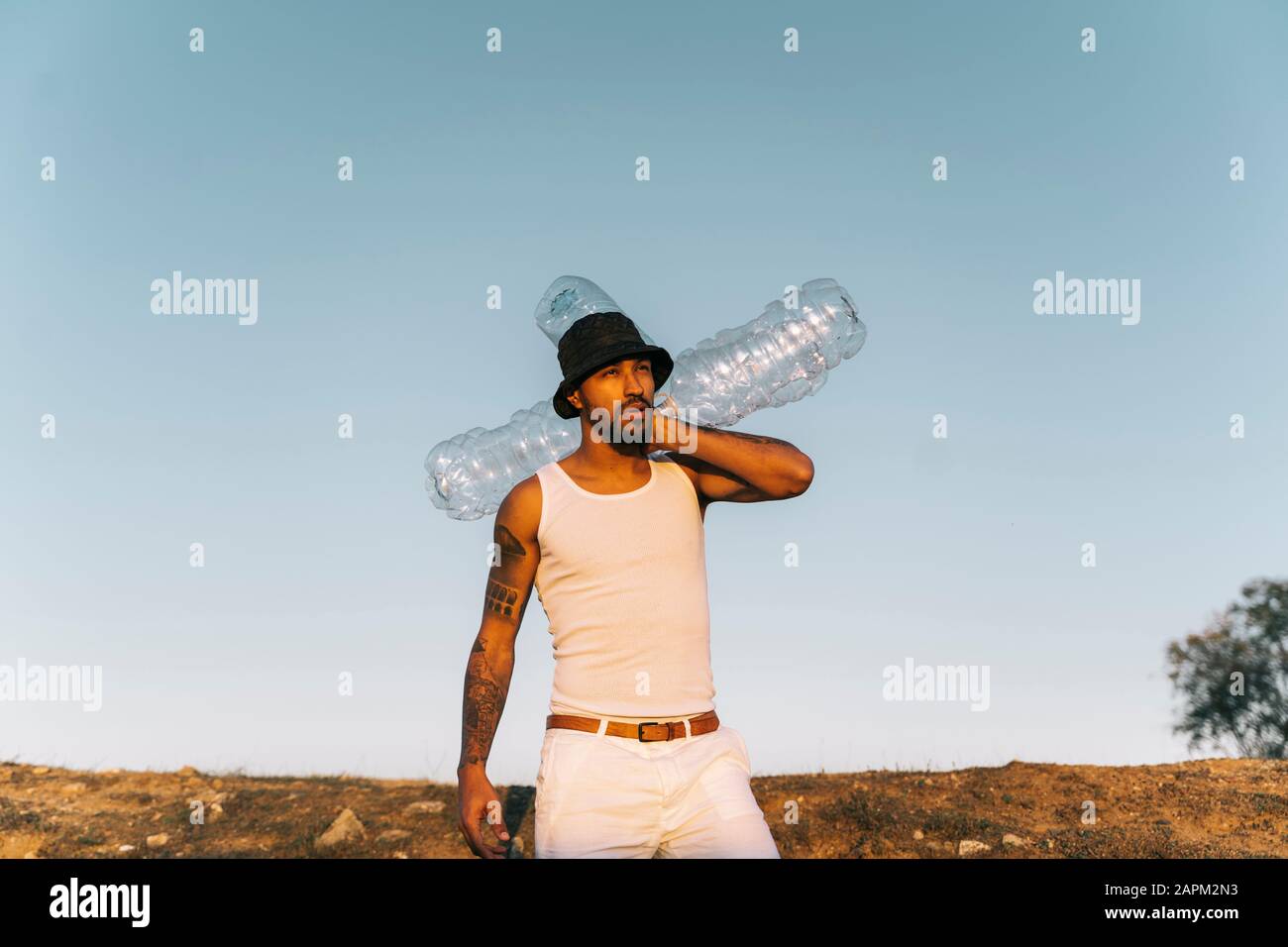 Young man holding empty plastic bottles in barren land Stock Photo