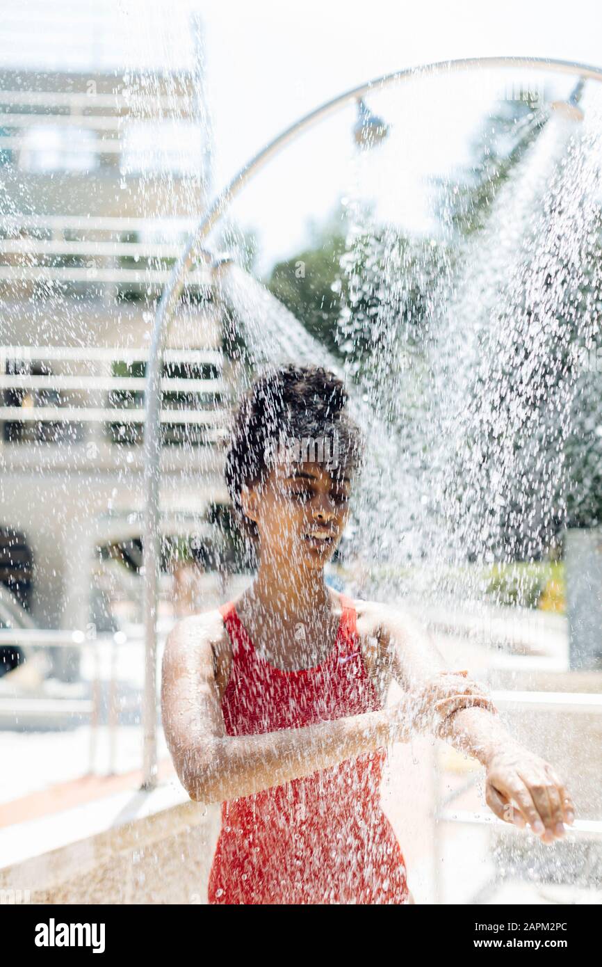 Young woman in red bathsuit showering outdoors Stock Photo
