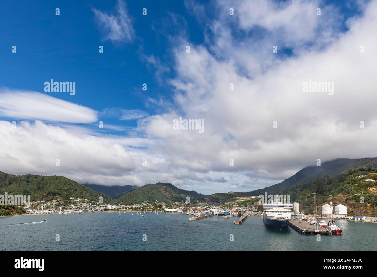 New Zealand, Marlborough Region, Picton, White summer clouds over ferry moored in harbor of coastal town Stock Photo