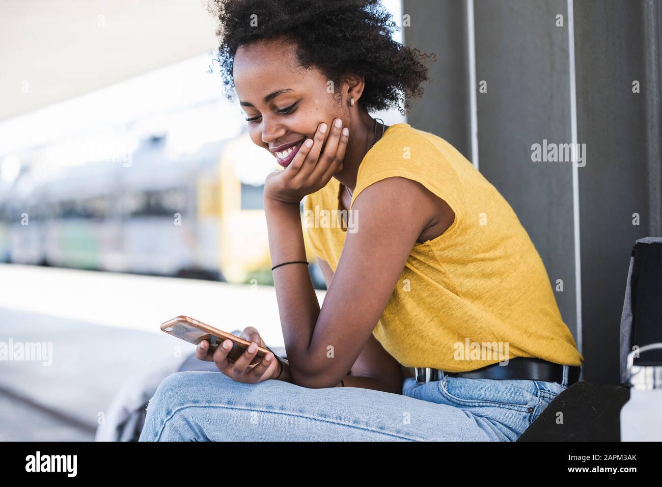 Smiling young woman using cell phone at the train station Stock Photo