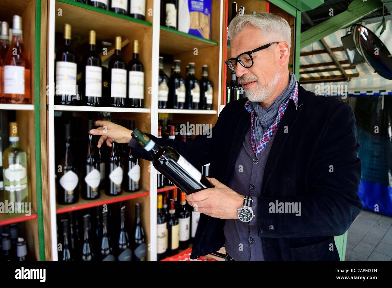 Mature man choosing bottle of wine at a wine shop Stock Photo