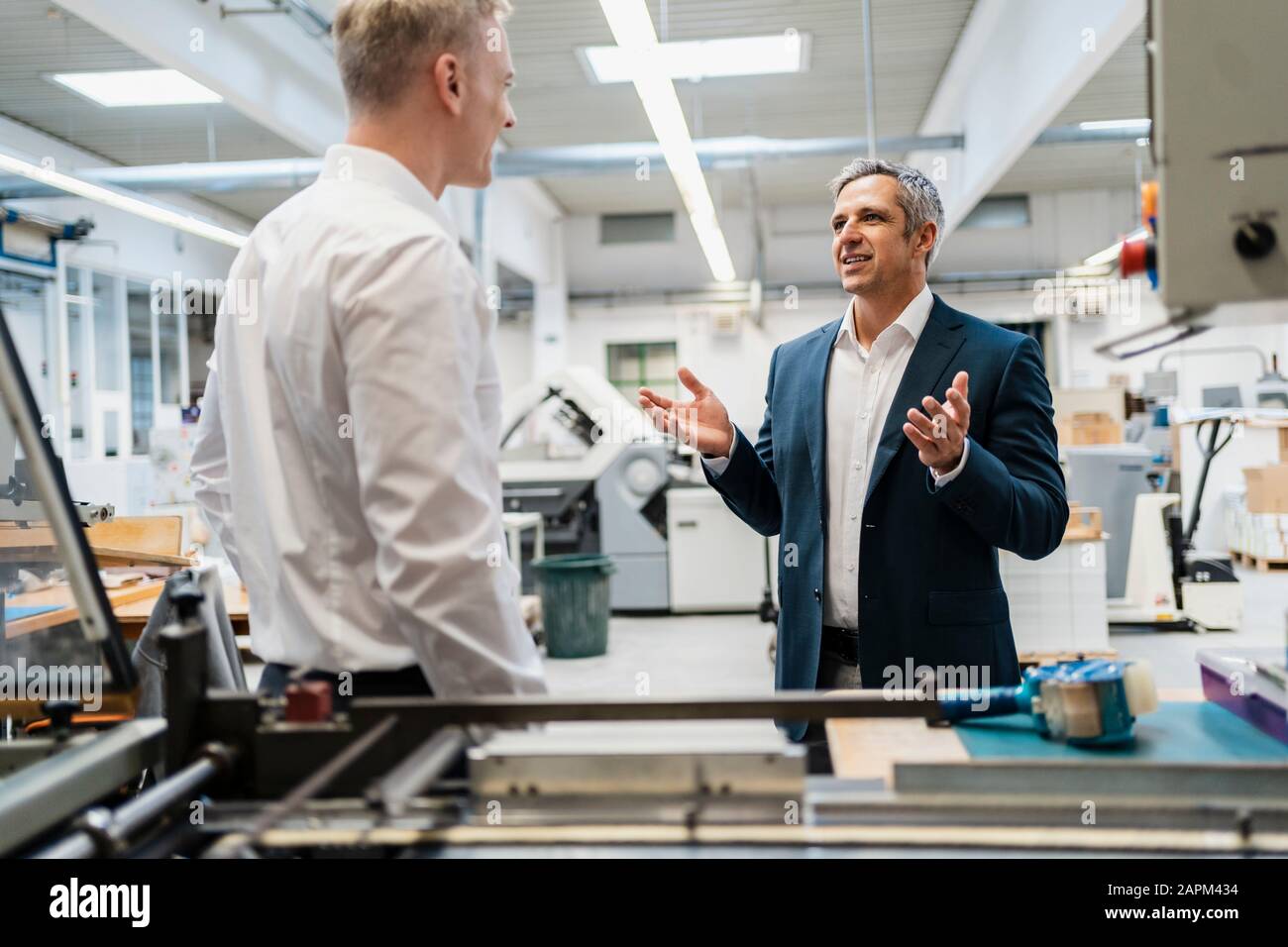 Two businessmen talking in a factory Stock Photo - Alamy