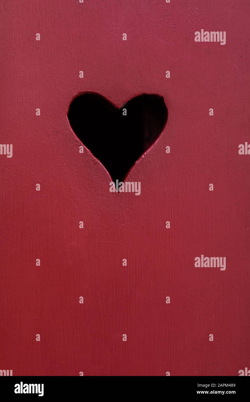 Heart shaped hole red wooden surface hires stock photography and