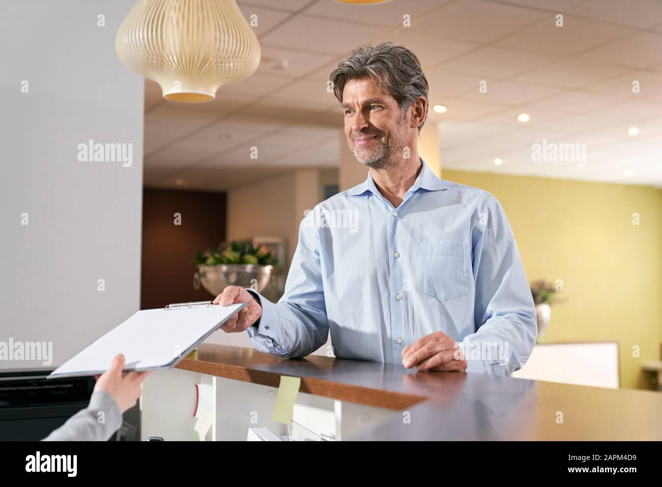 Patient handing over registration form at reception in a medical practice Stock Photo