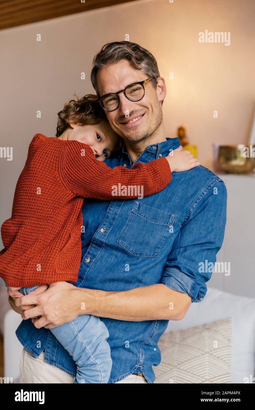 Portrait of smiling father carrying daughter at home Stock Photo