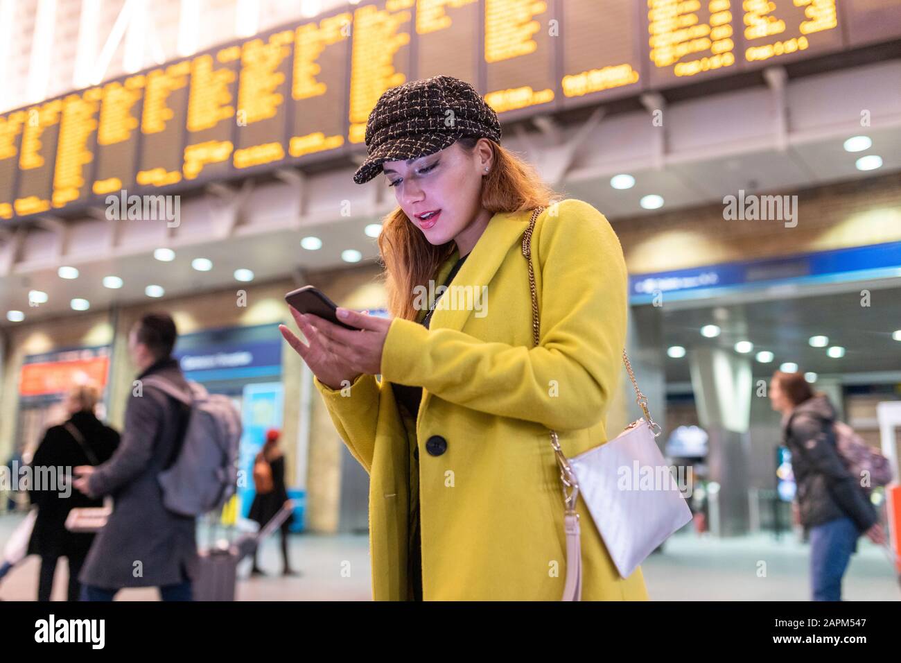 Woman at train station checking her smartphone Stock Photo
