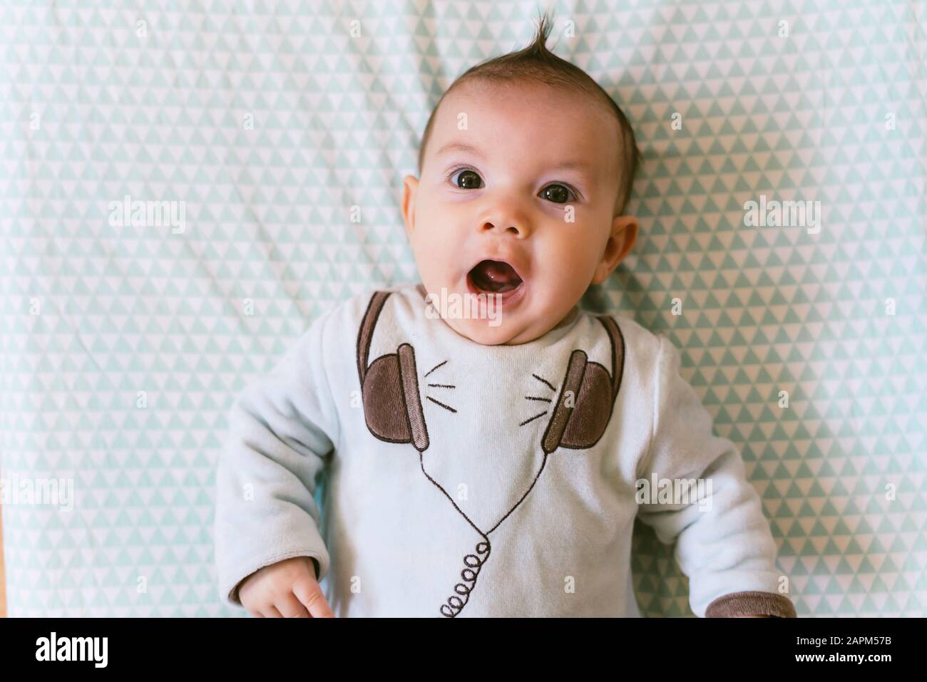 Portrait of surprised baby girl with appliqued headphones on pyjama Stock Photo