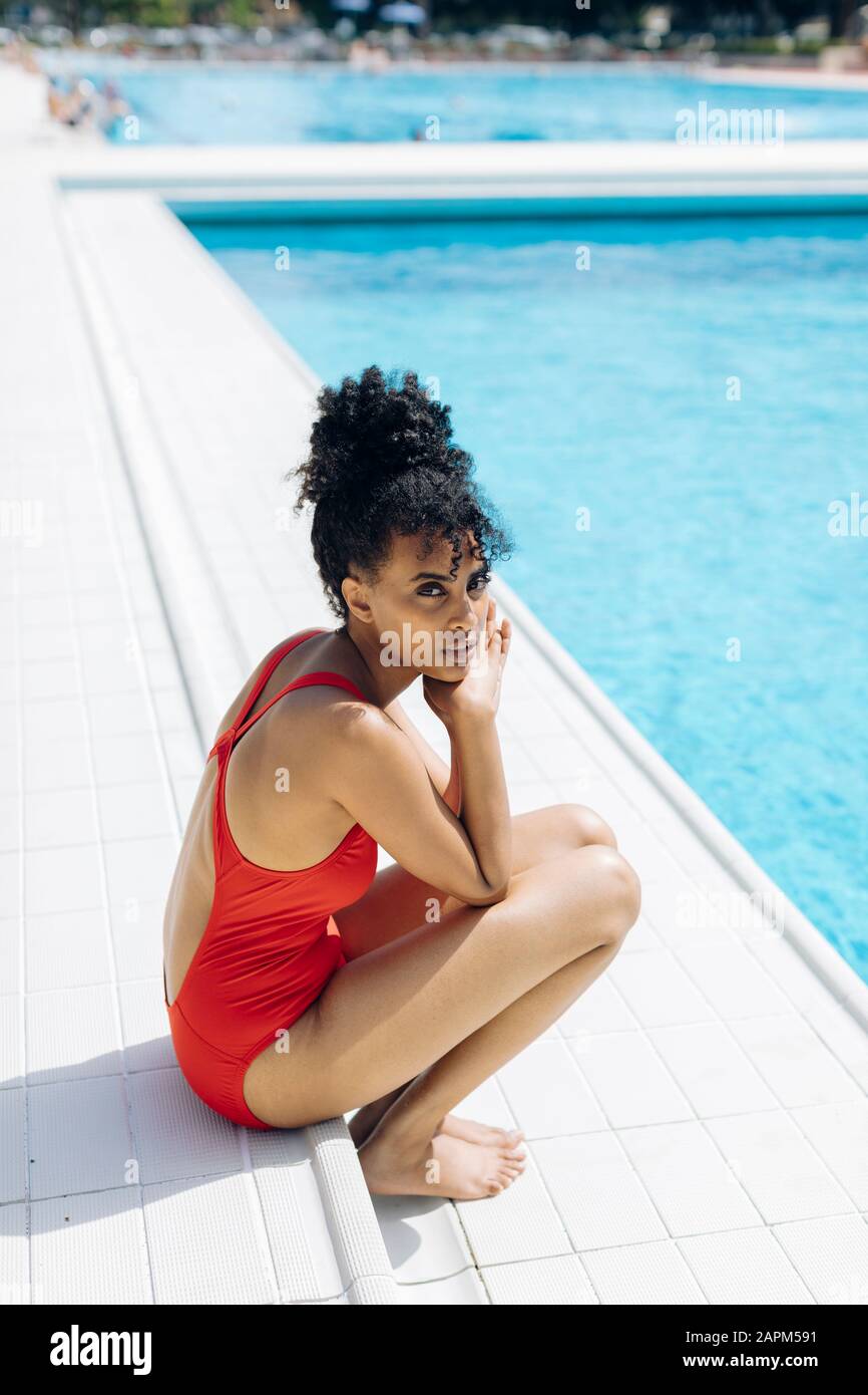 Happy woman swimming in pool in red swimsuit with loose long hair relaxed  with hands up in sunlight Stock Photo by shotprime