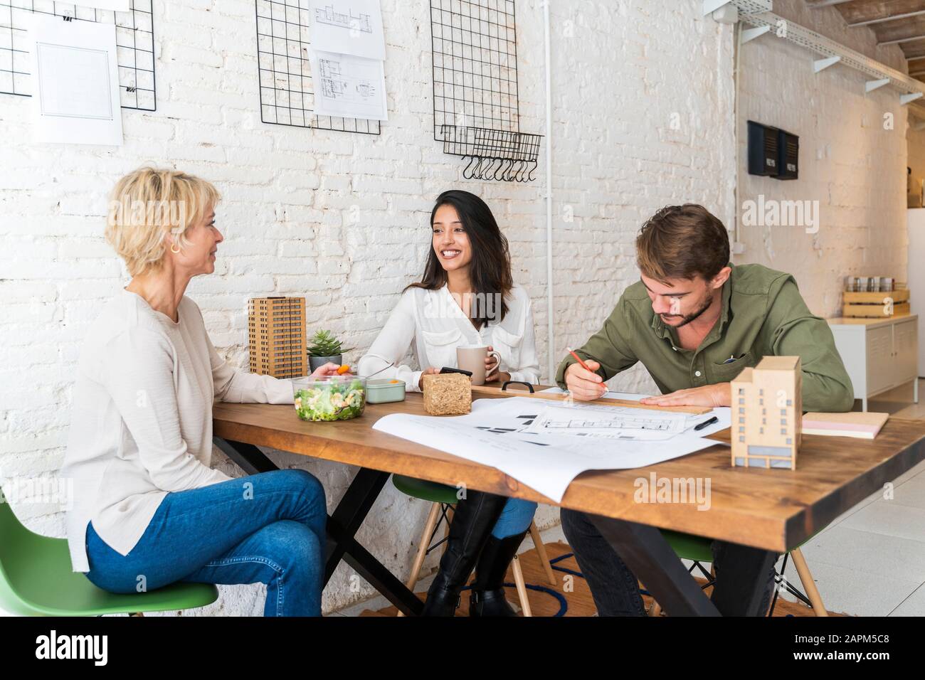 Three colleagues sharing desk in architect's office Stock Photo
