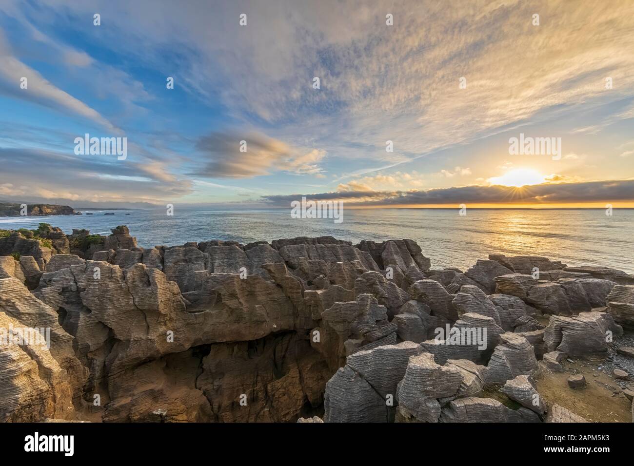 New Zealand, Buller District, Punakaiki, Limestone Pancake Rocks formation and coastal blow hole at sunset Stock Photo