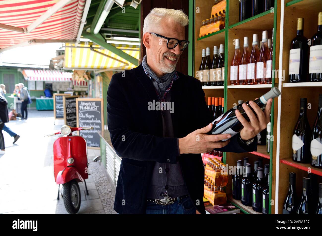 Smiling mature man choosing bottle of wine at a wine shop Stock Photo