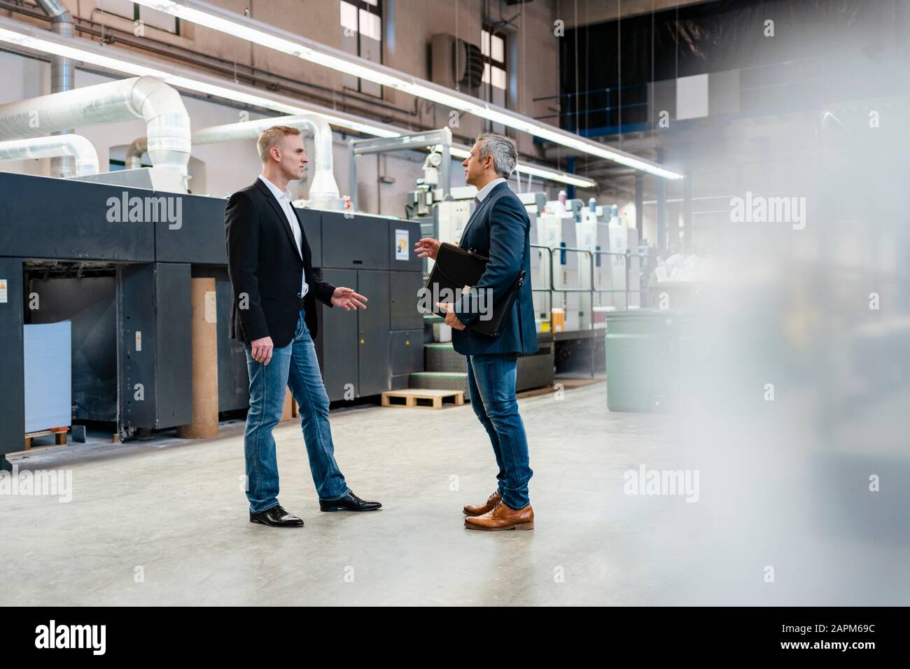 Two businessmen talking in a factory Stock Photo - Alamy