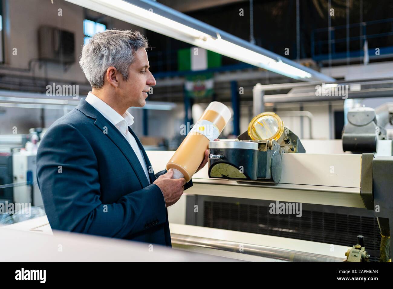 Businessman in a factory examining product Stock Photo