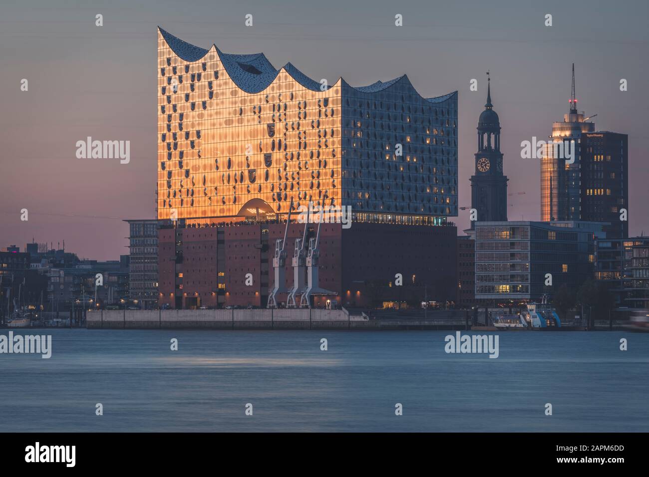 Germany, Hamburg, Elbphilharmonie at dusk with Saint Michaels Church in background Stock Photo