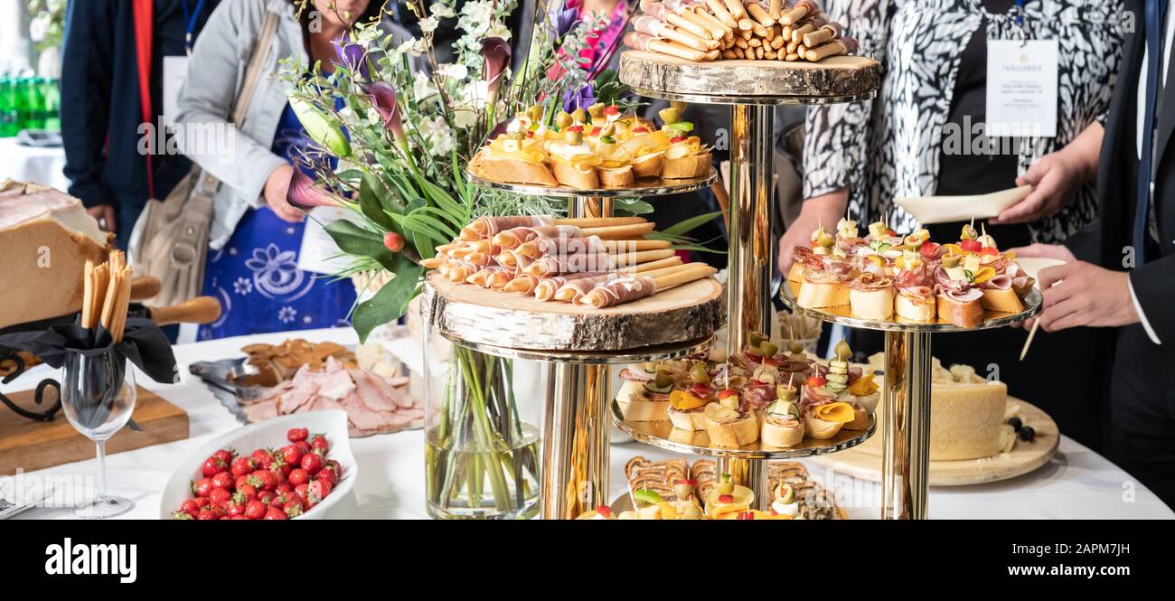 Businesspeople at banquet lunch break at business conference meeting. Assortment of canapes and finger food on the table. Stock Photo