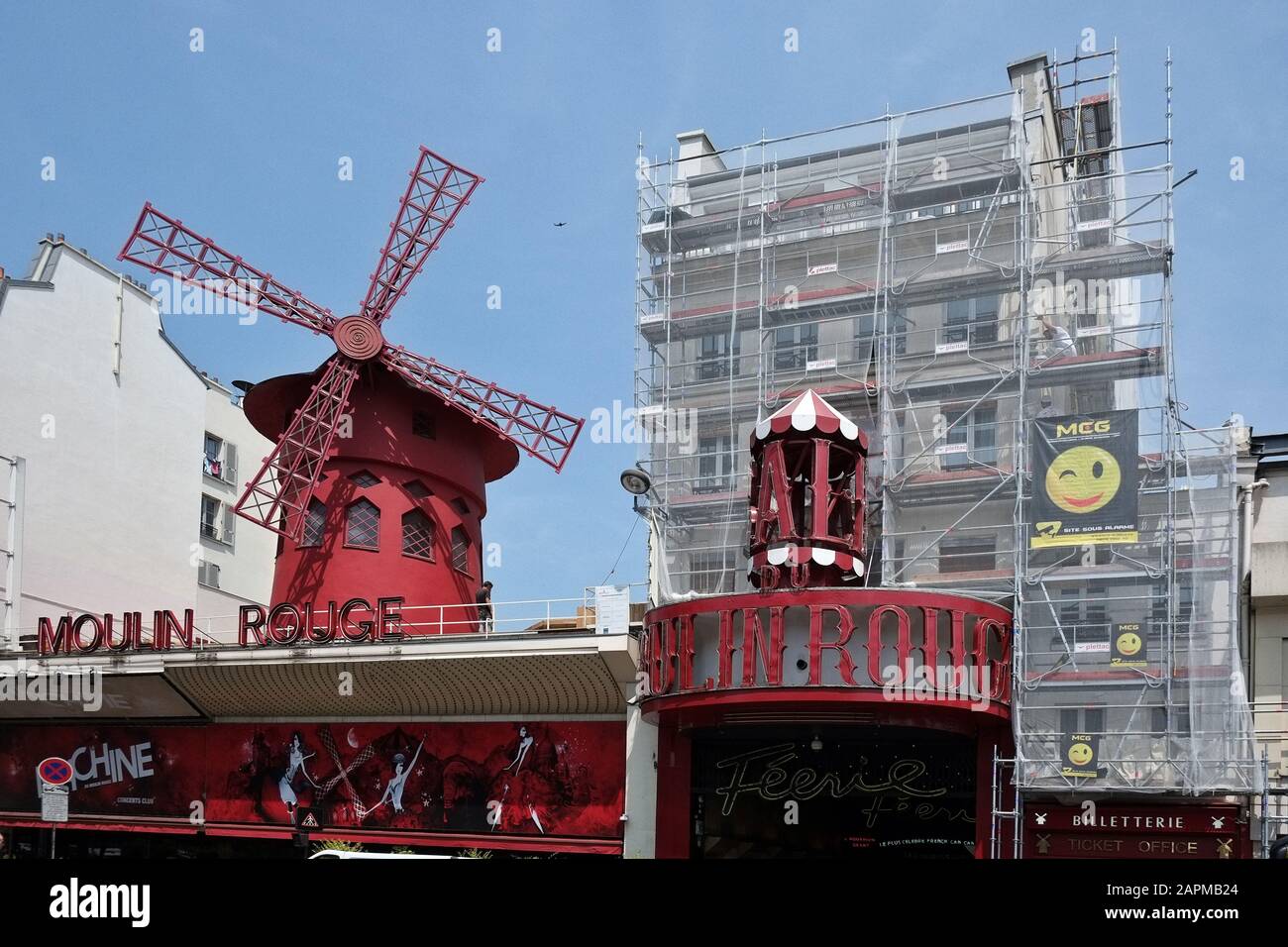 Moulin Rouge, The Famous Windmill by Day in Red the Sky in Blue and surrounding buildings in White, A French Tricolour of History and Entertainment Stock Photo
