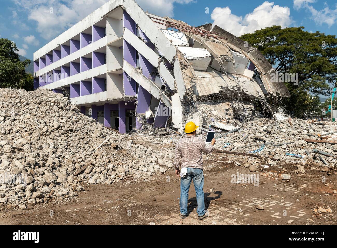 Engineer holding tablet is checking for destruction, demolishing building. Stock Photo
