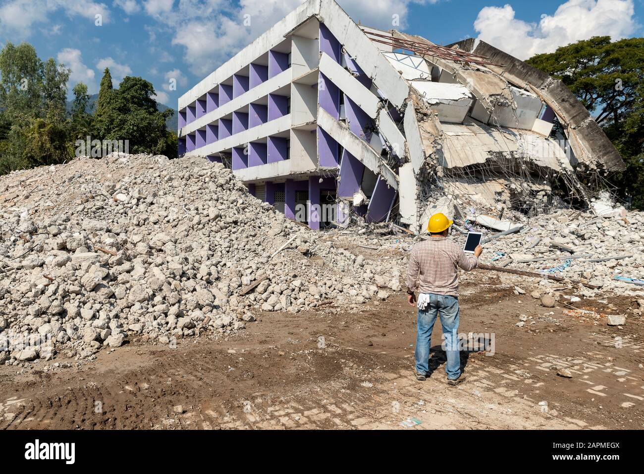 Engineer holding tablet is checking for destruction, demolishing building. Stock Photo